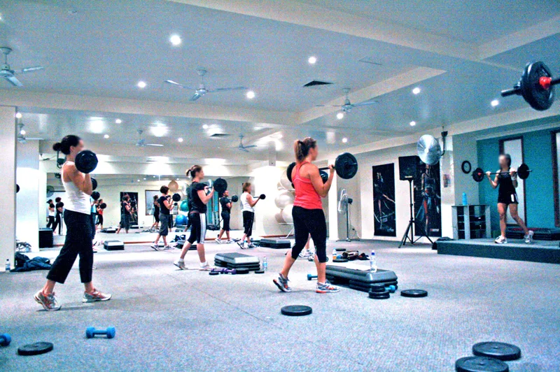 Clase de entrenamiento en grupo con barras en un centro de fitness.