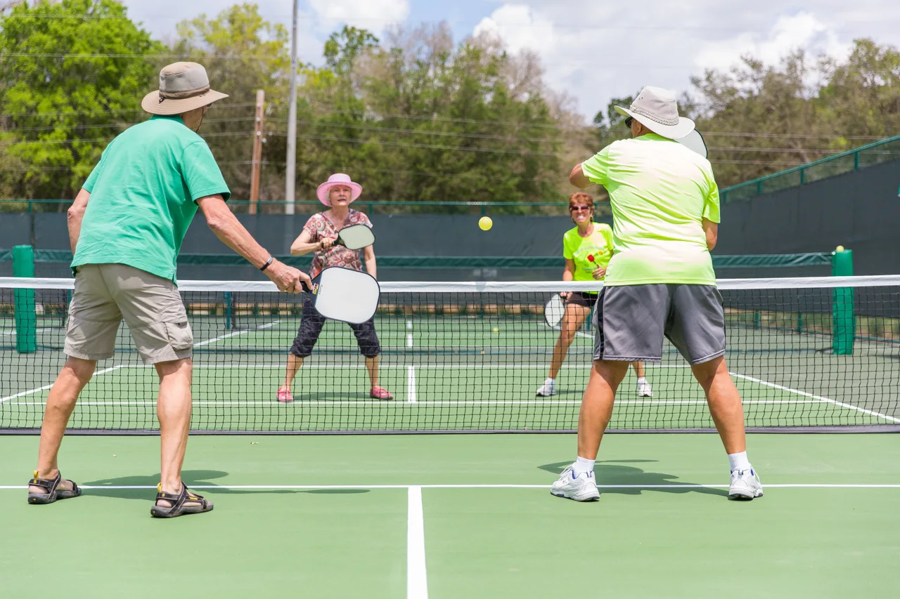 Jugadores de pickleball en varias pistas al aire libre.